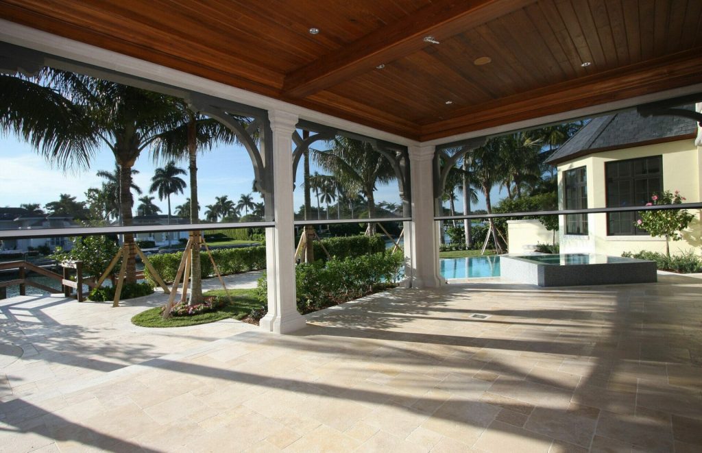 Canal-front Naples lanai with motorized screens and royal palms